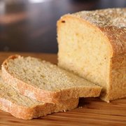 A loaf of anadama bread resting on a wooden cutting board, showcasing its rustic texture and golden-brown crust