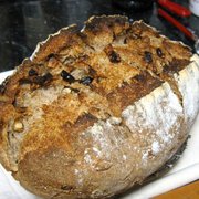 A loaf of sourdough rye with walnuts resting on a napkin atop a kitchen counter