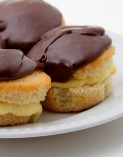 A plate featuring three Boston Cream Pies, each adorned with rich chocolate frosting