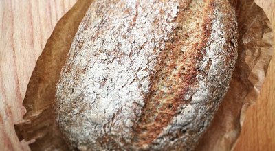 A loaf of bread resting on a rustic wooden table, showcasing its golden crust and inviting texture